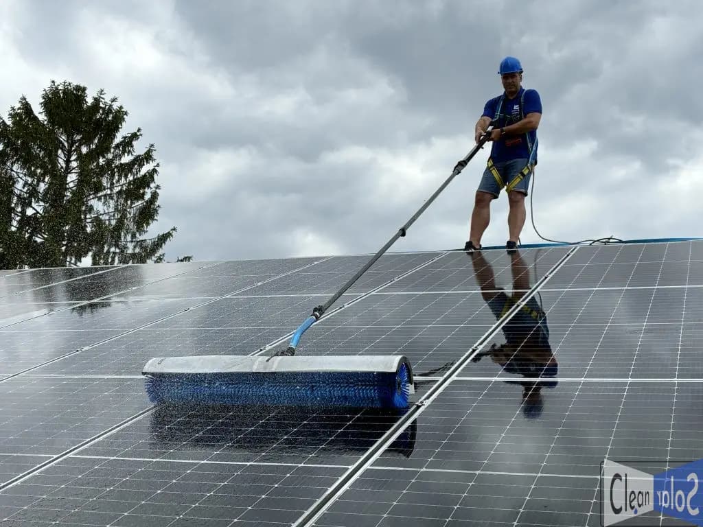 CleanSolar szakember napelemeket tisztít teleszkópos, panelbarát kefével egy családi ház tetején